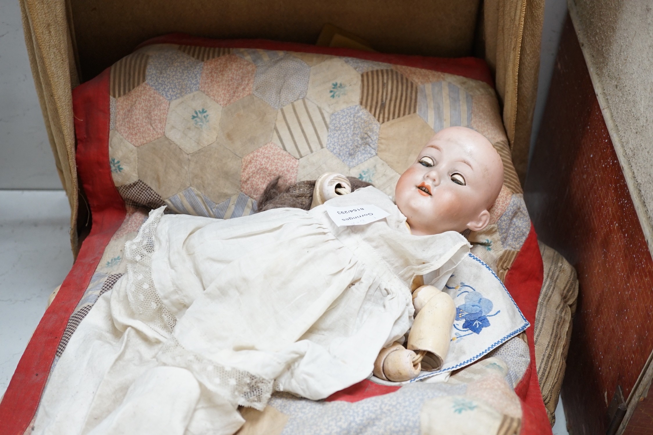 An Armand Marseille 390 A 11/2 M porcelain doll and a half tester wooded bed, bed 55cms deep x 55cms high x 36cms wide